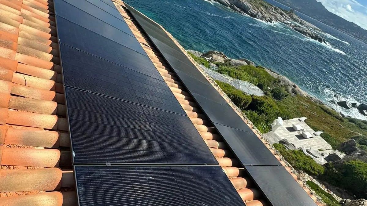 Rangées de panneaux noirs sur tuiles canal en bord de falaise, mer et côte rocheuse en contrebas