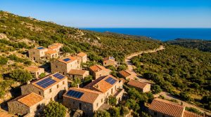 Vue aérienne d'un village corse avec plusieurs maisons équipées de panneaux solaires sur les toits en tuiles